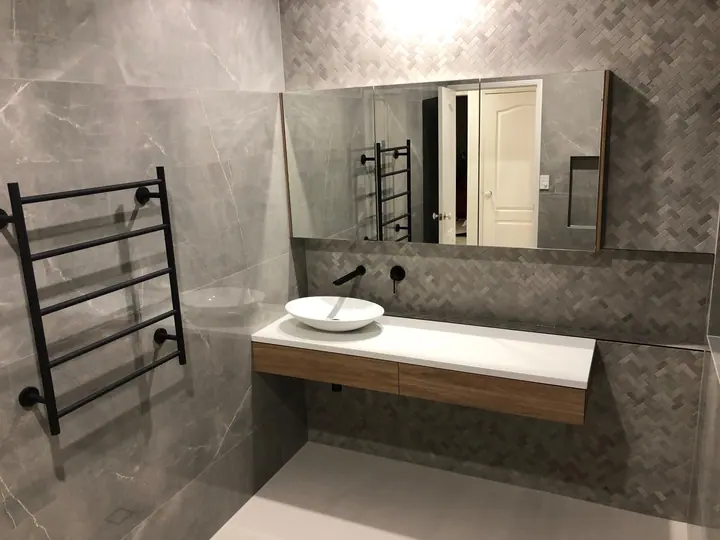 Bathroom with grey marble-look tiles, a herringbone feature wall and a floating vanity