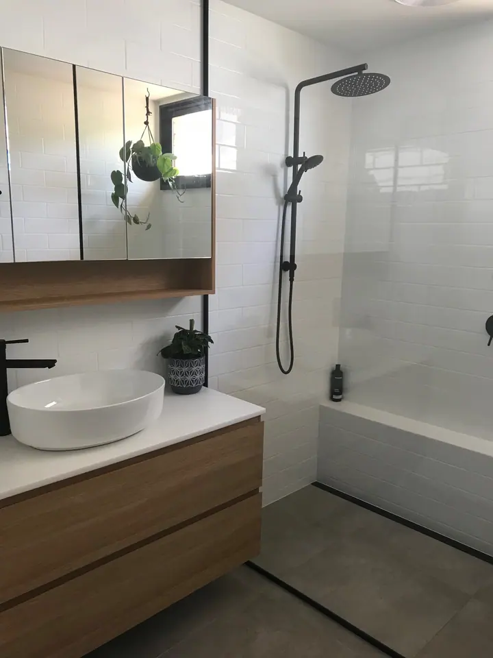 Bathroom with white wall tiles, black tapware, grey floor tiles and a linear shower drain