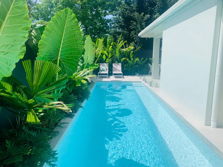 Lap pool with pale blue tiles and tiled coping in a tropical garden