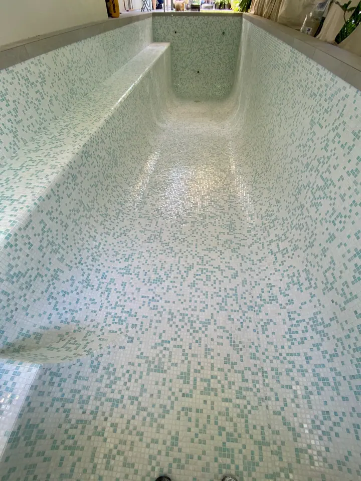 Lap pool tiled in a white and aqua mosaic blend before filling