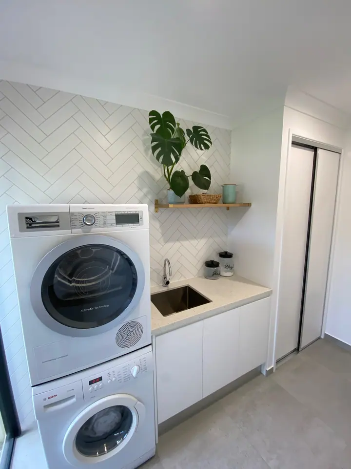 Laundry with a white herringbone tiled splashback and grey floor tiles