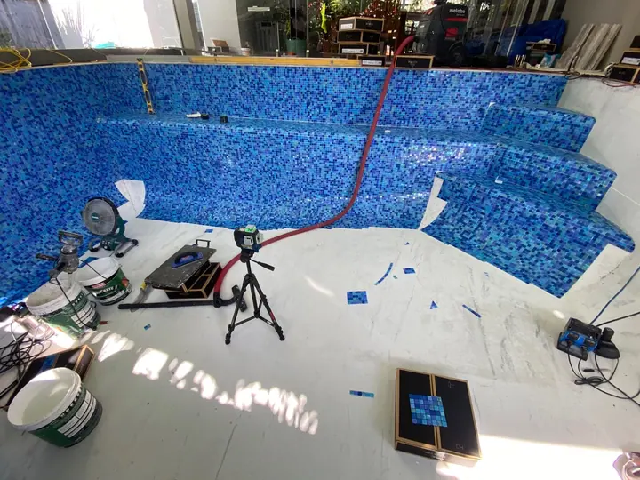 Blue mosaic pool interior and steps being tiled