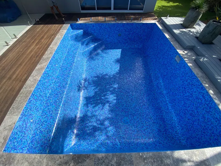 Pool finished in deep blue mosaic tiles beside a timber deck