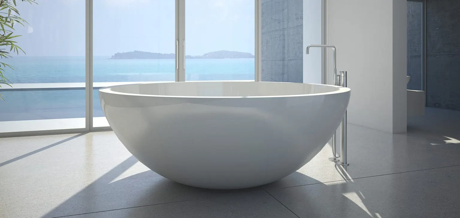 Round freestanding bath in a tiled bathroom with ocean views